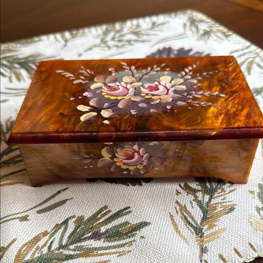 A vintage, hand-painted floral music jewelry box, likely made of lucite
